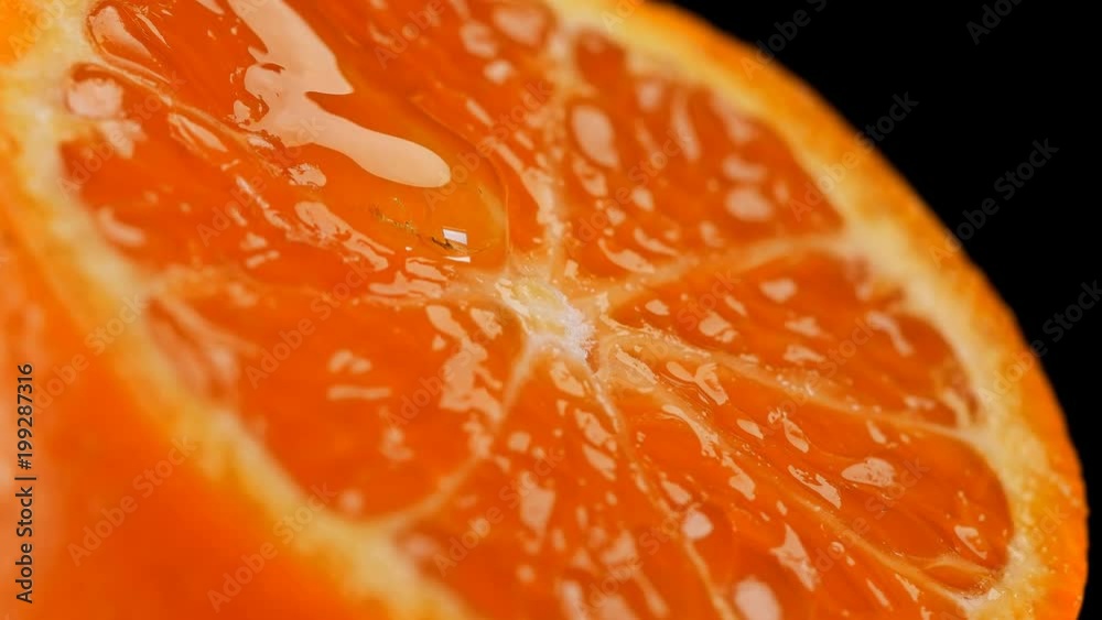 juicy, refreshing tangerine in the context of which the honey flows slowly rotates, close-up