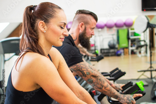 Thoughtful woman in a gym beside a tattooed man. © noskaphoto