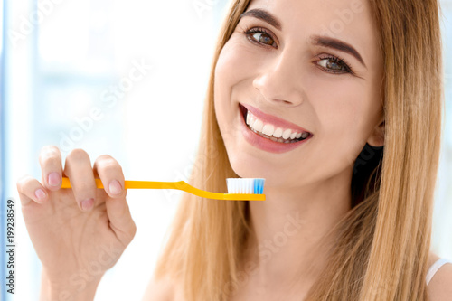 Young woman brushing her teeth indoors