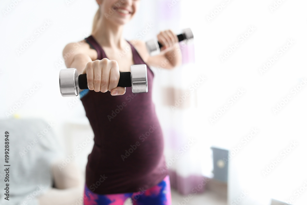 Young pregnant woman doing exercises with dumbbells at home Young pregnant woman doing exercises with dumbbells at home