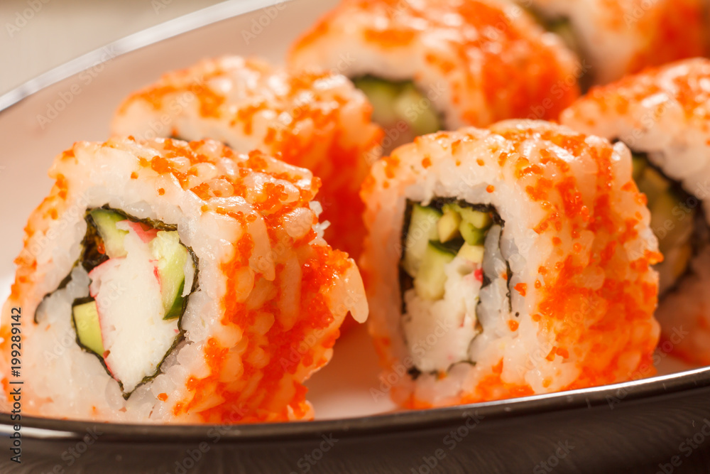 Close up Uramaki California. Sushi rolls with nori, rice, pieces of avocado, cucumber, crab sticks and flying fish roe Close up Uramaki California. Sushi rolls with nori, rice, pieces of avocado, cucumber, crab sticks and flying fish roe