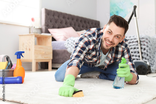Mature man cleaning carpet at home