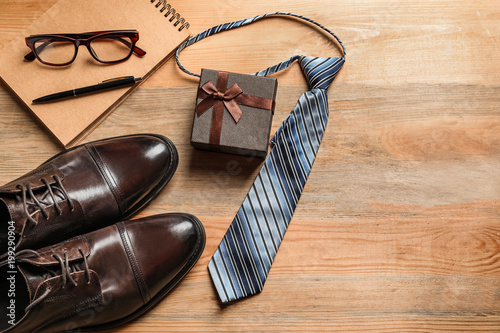 Flat lay composition with shoes, notebook, tie and gift box on wooden background. Father's day celebration