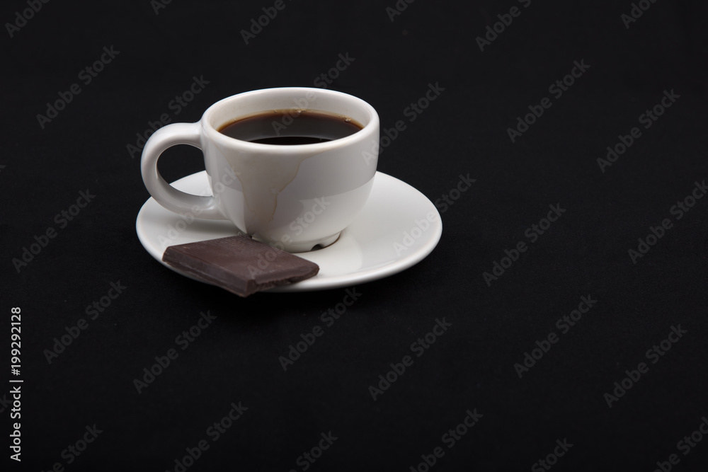 Cup of coffee with chocolate on black surface..