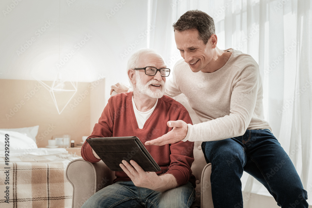 Do you remember. Funny pleasant satisfied men sitting on the chair spending time together and overlooking the tablet. Do you remember. Funny pleasant satisfied men sitting on the chair spending time together and overlooking the tablet.