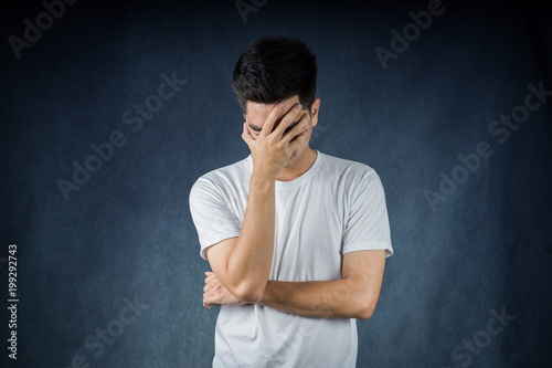 Terrible headache portrait handsome young asian man wearing a white t-shirt  isolated on black background. Businessman concept. Asia people.