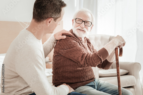 My father my friend. Calm pleasant unshaken man sitting on the bed communicating with son and smiling.