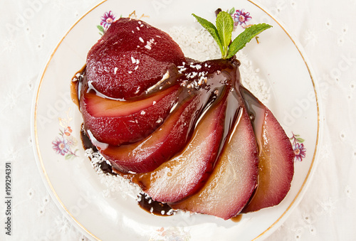 Pears in wine. Traditional dessert pears stewed in red wine with chocolate sauce on plate on white background. Top view