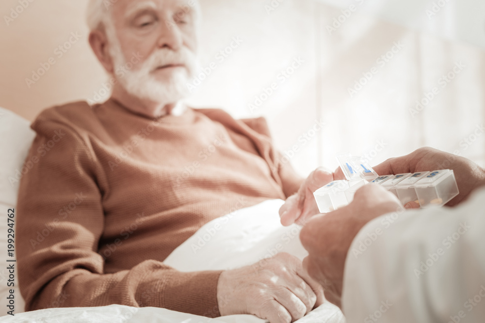 Take one. Old ill exhausted man sitting on the bed feeling bed himself and taking pills. Take one. Old ill exhausted man sitting on the bed feeling bed himself and taking pills.