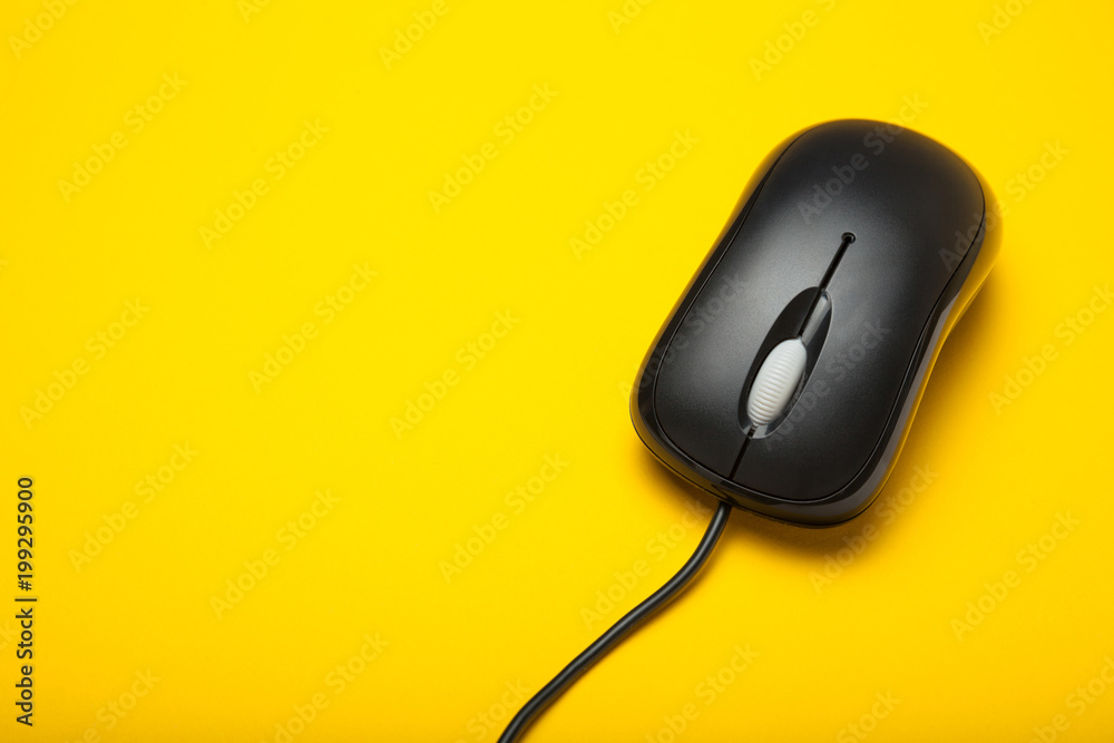 Computer mouse black with a cord on a yellow background. Computer mouse black with a cord on a yellow background.