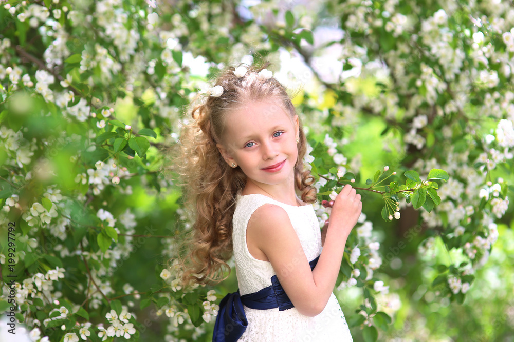 Portrait of little happy girl in blooming apple orchard..Pretty cute child with with hair on his head celebrates birthday or other holiday. Portrait of little happy girl in blooming apple orchard..Pretty cute child with with hair on his head celebrates birthday or other holiday.