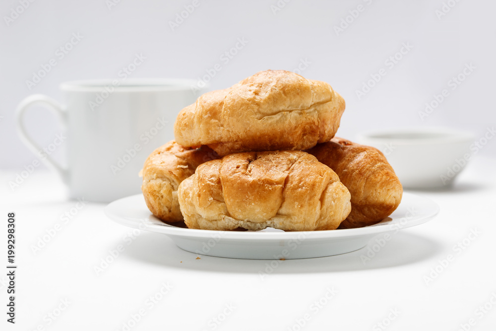 Fresh croissant in a white plate on a white table Fresh croissant in a white plate on a white table