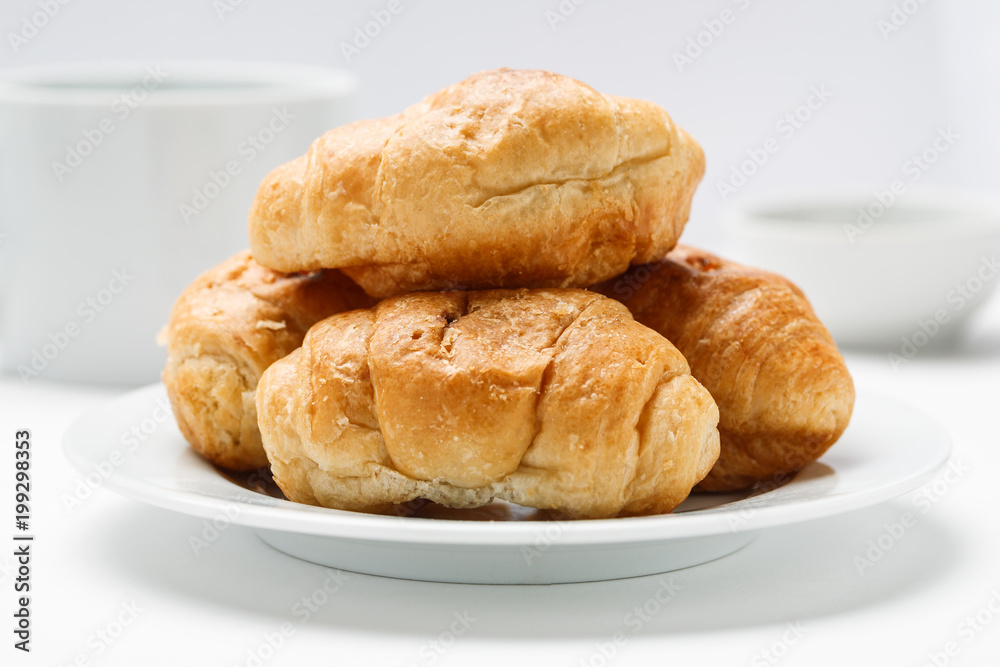 Fresh croissant in a white plate on a white table, closeup