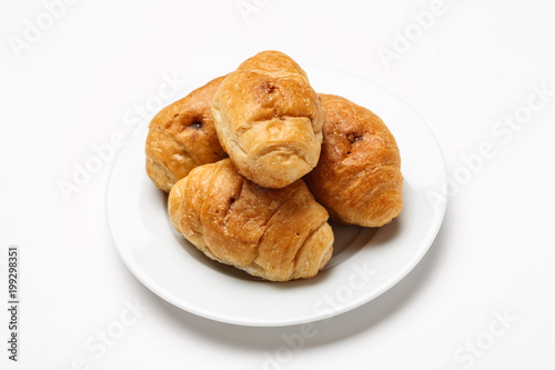 Fresh croissant in a white plate on a white table