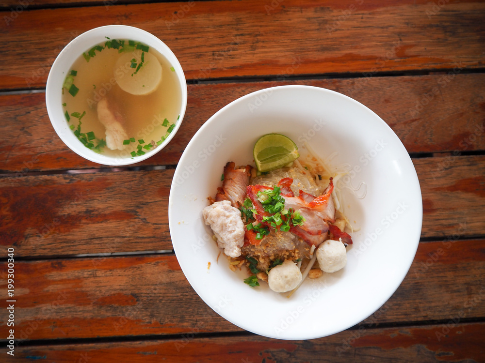 Closeup of hot noodles. Thai local noodle. Thai style pork spicy noodle soup. Pork noodle spicy soup ,Thai noodle,Tom yum. Bowl With spoon and chopsticks on wooden table. Closeup of hot noodles. Thai local noodle. Thai style pork spicy noodle soup. Pork noodle spicy soup ,Thai noodle,Tom yum. Bowl With spoon and chopsticks on wooden table.