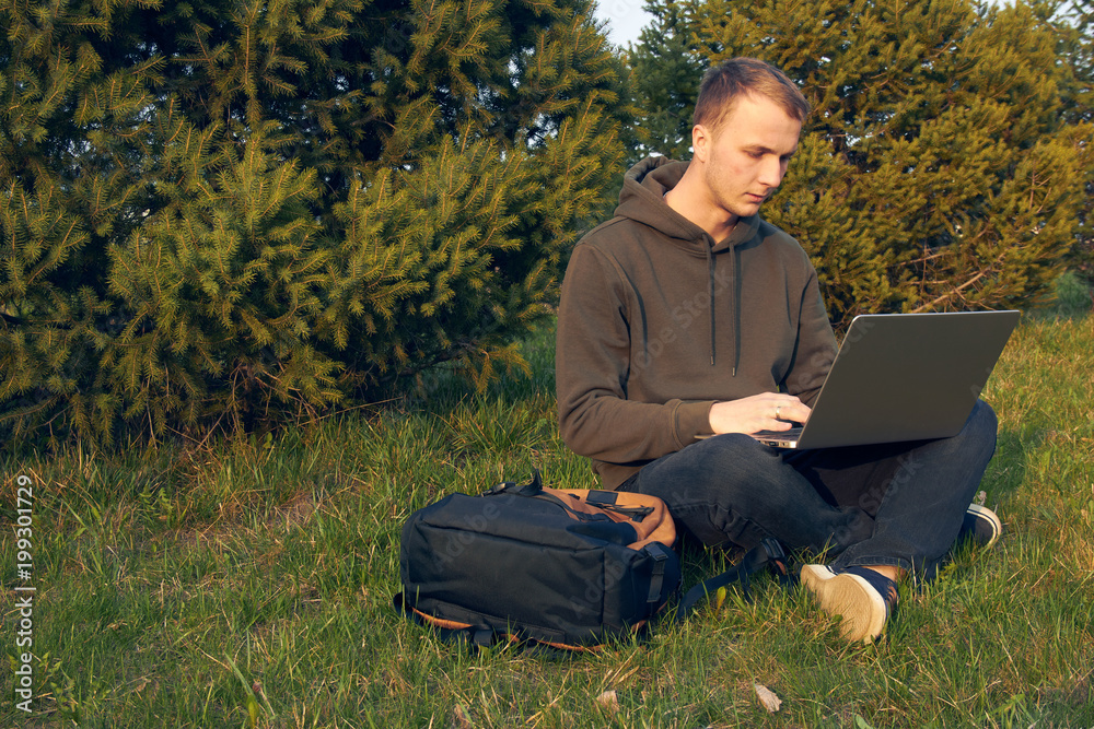 young man working in laptop sitting on grass young man working in laptop sitting on grass