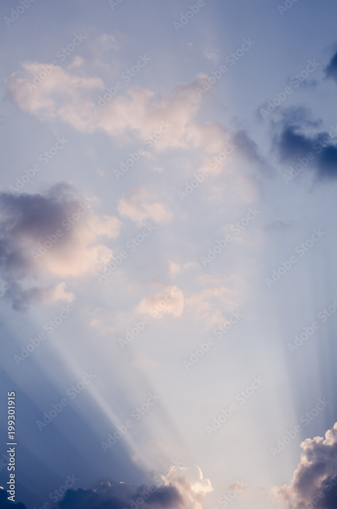Interesting sun rays penetrating through beautiful clouds on the blue sky in a sunny day. Great vertical cloudscape backdrop wallpaper for your graphic design project