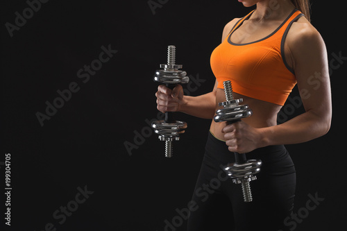 Unrecognizable athletic woman with dumbbells