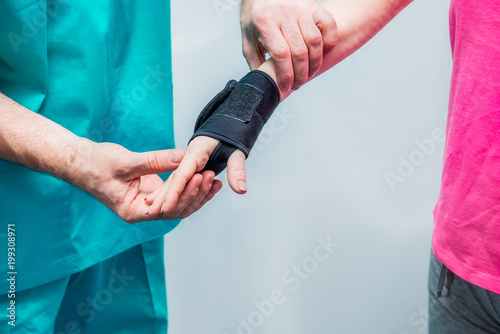 Close up Neurologist doctor, therapist puts on wrist retainer on young female patient's hand. Pain treatment. Neurology, Osteopathy, chiropractic. Selective focus. space for text. photo