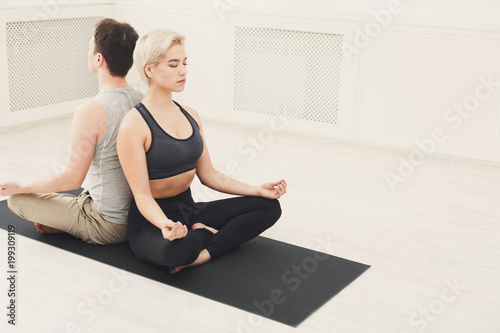 Young couple meditating together, back to back