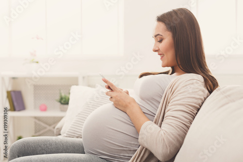 Happy pregnant woman using smartphone