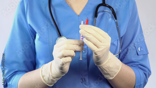 Female doctor in rubber gloves preparing syringe insulin injection, vaccination