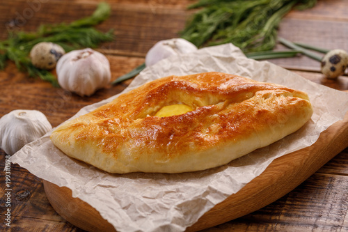 Traditional grzina baking. Khachapuri with egg close-up on a wooden background.