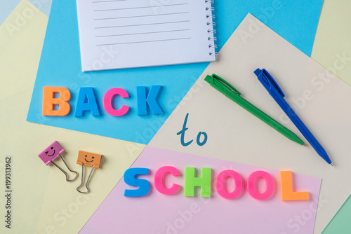 The inscription back to school plastic letters on the background of paper and a blank notebook