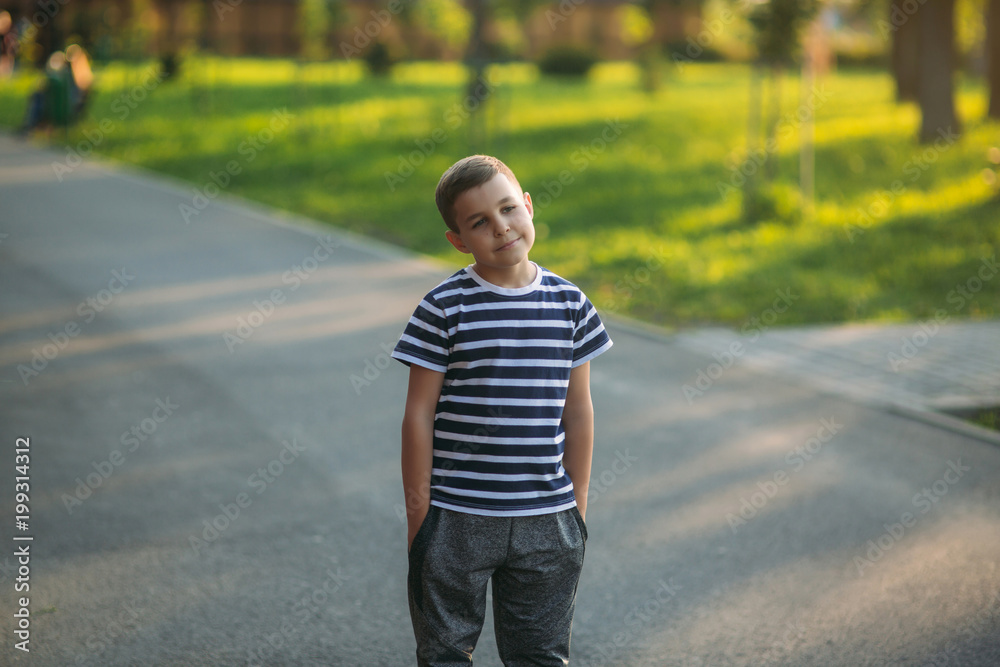 A little boy in a striped T-shirt is playing on the playground, Swing on a swing A little boy in a striped T-shirt is playing on the playground, Swing on a swing