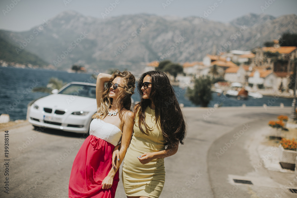 Two pretty young women by white cabriolet car