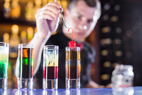 Bartender lays cherry in a shot at the bar