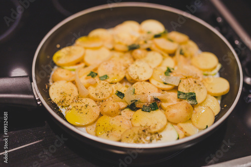 frying pan with potatoes, onions and zcchini recipe being cooked