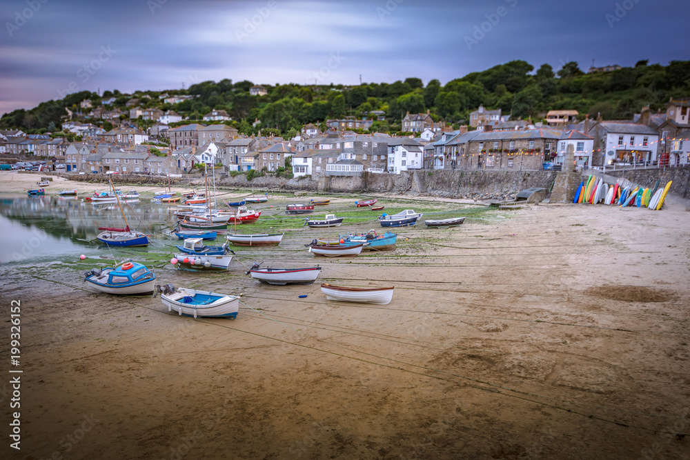 Boats resting on beach at the picturesque fishing village of Mousehole in Cornwall