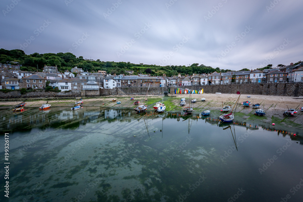 Calm clear water with boats on beach at the picturesque fishing village of Mousehole in Cornwall