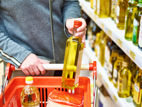 Bottle of olive oil in hand buyer at grocery