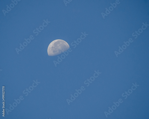 the half moon on the blue day sky