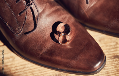 gold wedding rings on the brown leather shoes photo