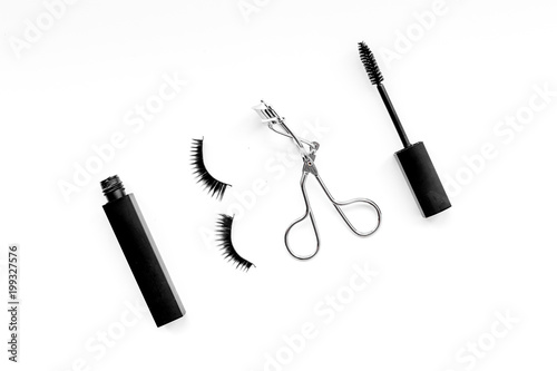 Cosmetics and tools for voluminous lashes. Mascara, false eyelashes, eyelash curler on white background top view space for text