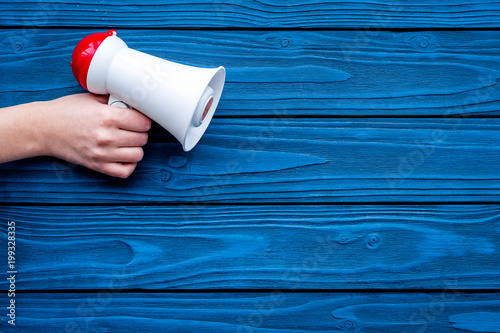 Announcement concept. Megaphone in hand on blue wooden background top view copy space
