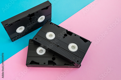 3 black VHS video tapes  a pink and blue background