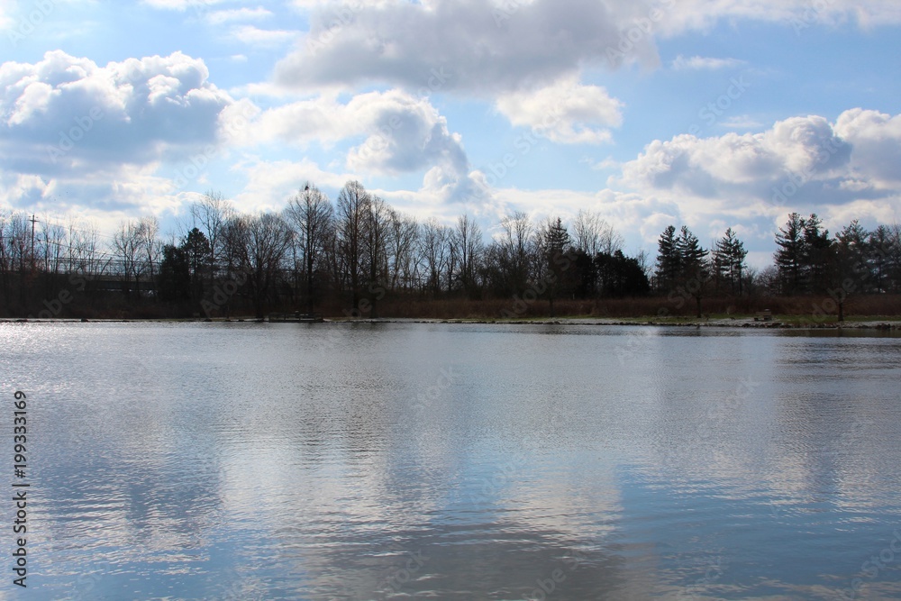 The lake with the puffy white clouds in the blue sky. The lake with the puffy white clouds in the blue sky.