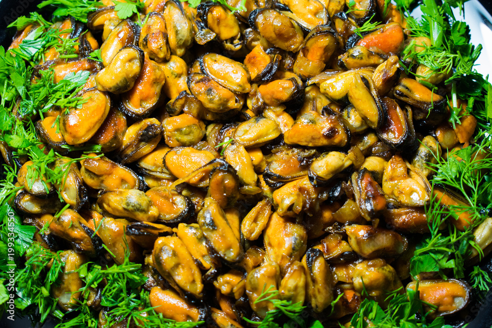 Coffee fried appetizing mussels on a dish, decorated with greenery. Coffee fried appetizing mussels on a dish, decorated with greenery.