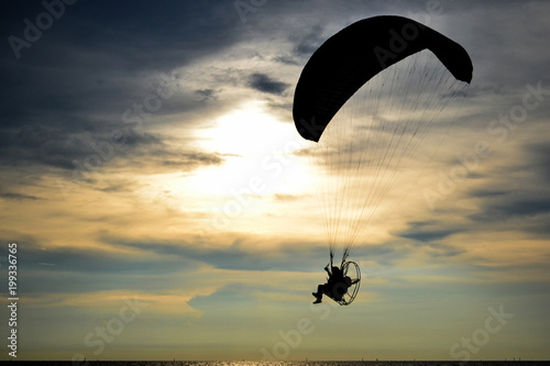 Silhouette one paramotor over sea and sunset sky
