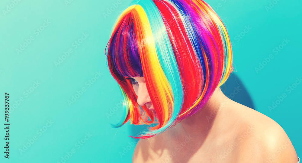 Beautiful woman in a colorful wig on a blue background Beautiful woman in a colorful wig on a blue background