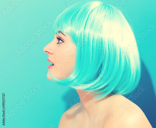 Beautiful woman in a bright blue wig on a blue background