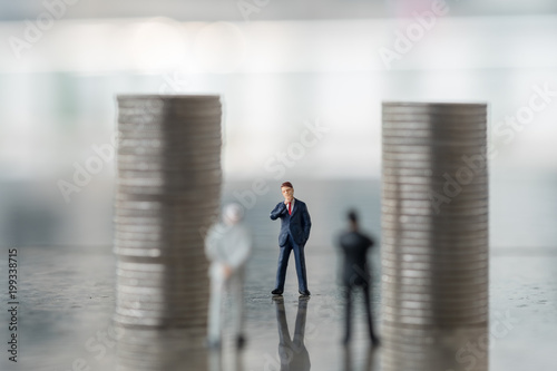 Business  Money and planning concept. Businessman miniature figure standing and looking to two other business man and stack of silver coins