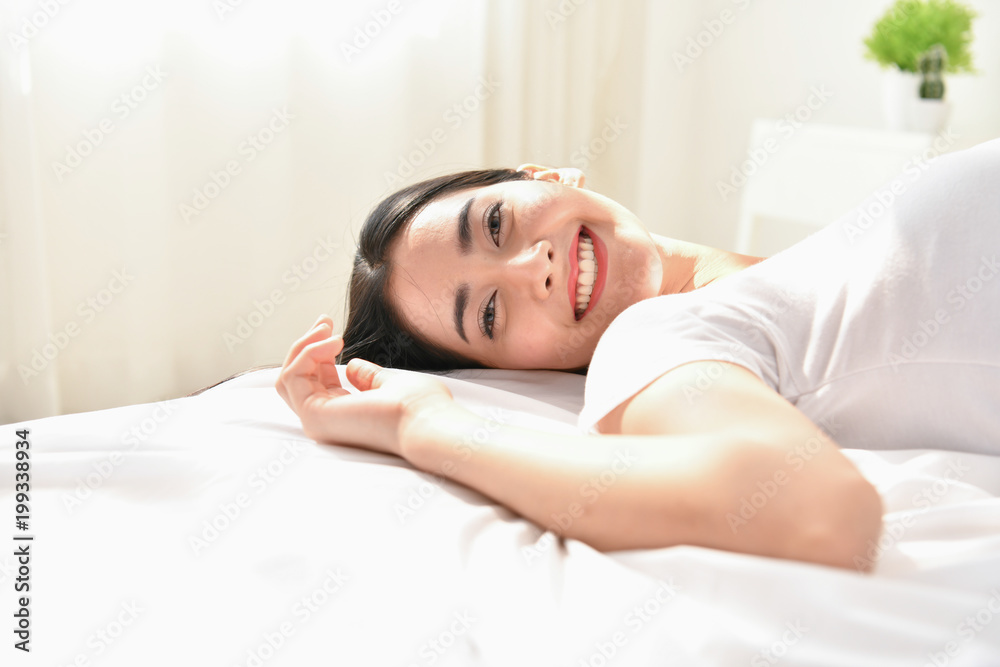 Lifestyle Concept. Cute Asian girl in night dress. Beautiful asian woman is relaxing in a white bedroom. Asian girls are playing in the bedroom happily.