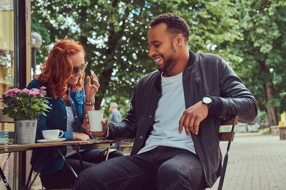 A couple dating drinking coffee, sitting near the coffee shop. Outdoors on a date. A couple dating drinking coffee, sitting near the coffee shop. Outdoors on a date.