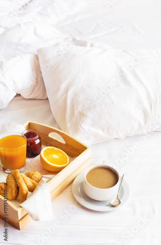 Morning breakfast in bed wooden tray with a cup of coffee croissant orange juice fresh orange jam Bed linen. Top view Hotel Room Early Morning at Hotel Background Concept Interior Copy Space