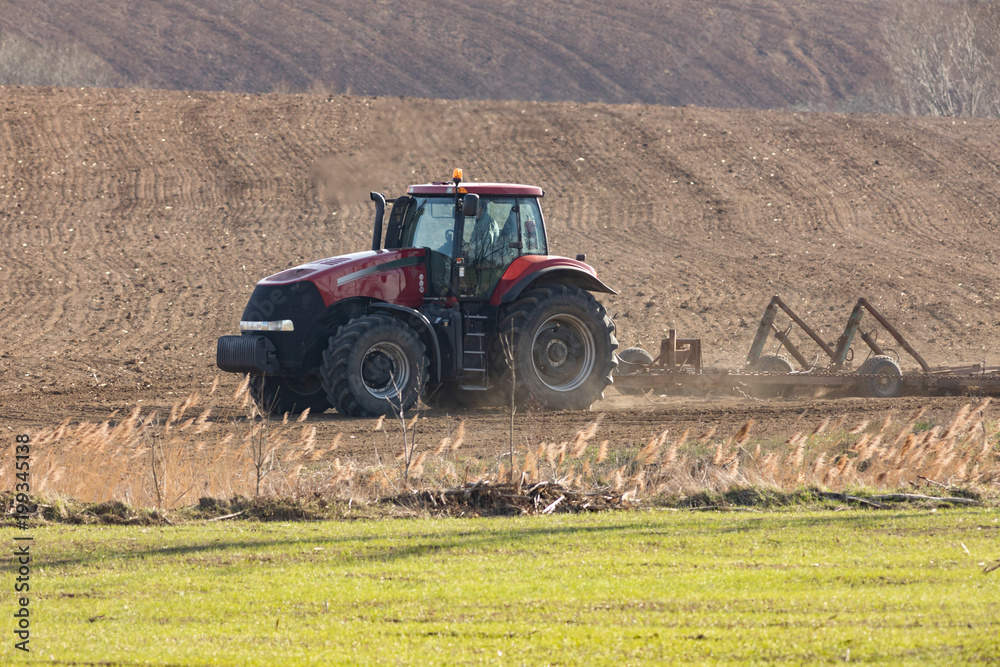 Obraz premium tractor harrowing on field